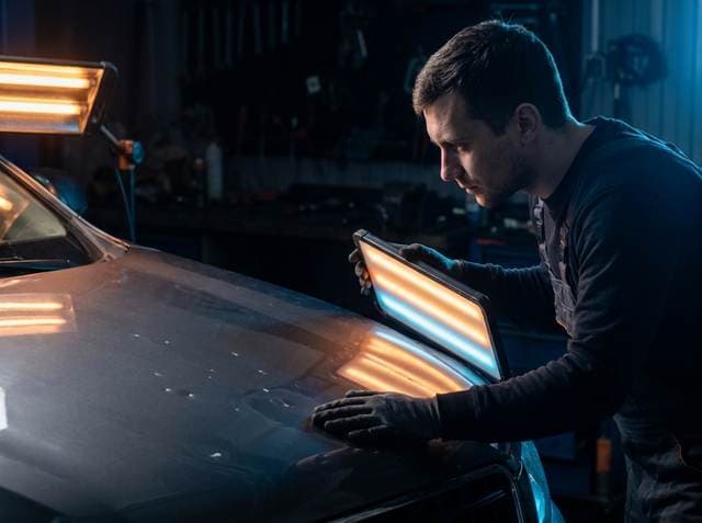 Technician assessing hail damage with an LED reflector board